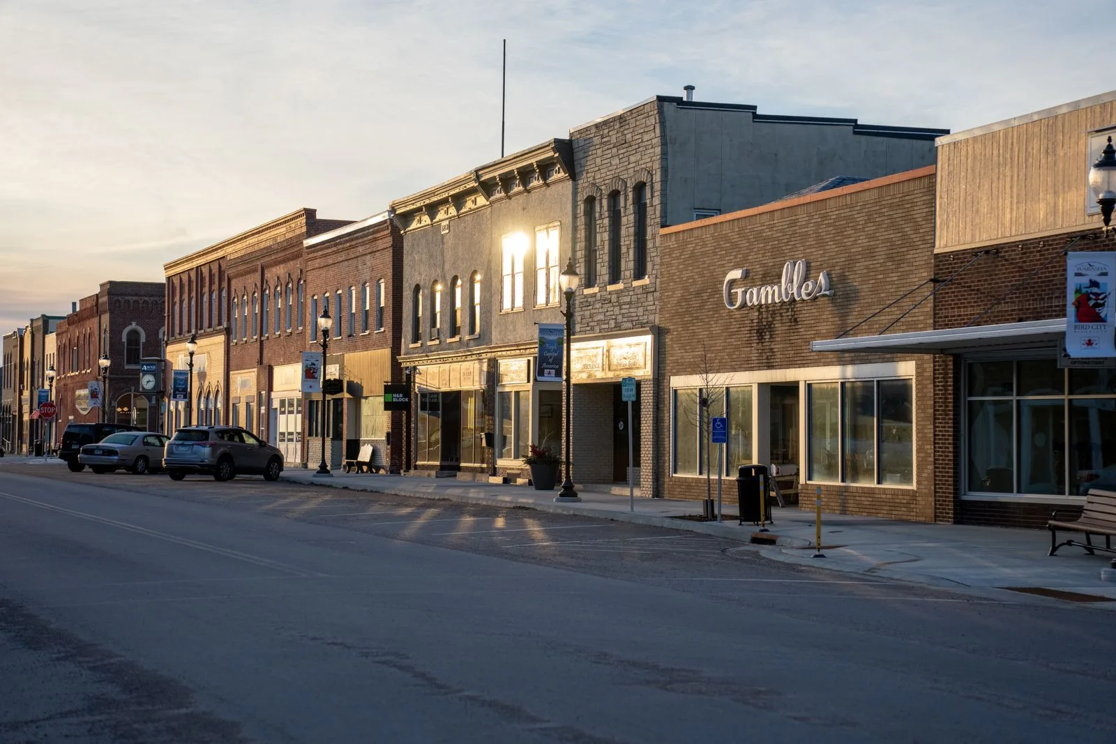 Small-town Main Street storefronts lit warm at sunset