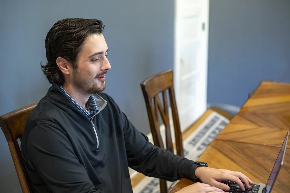 Taylor Ezell working at his laptop at a meeting table
